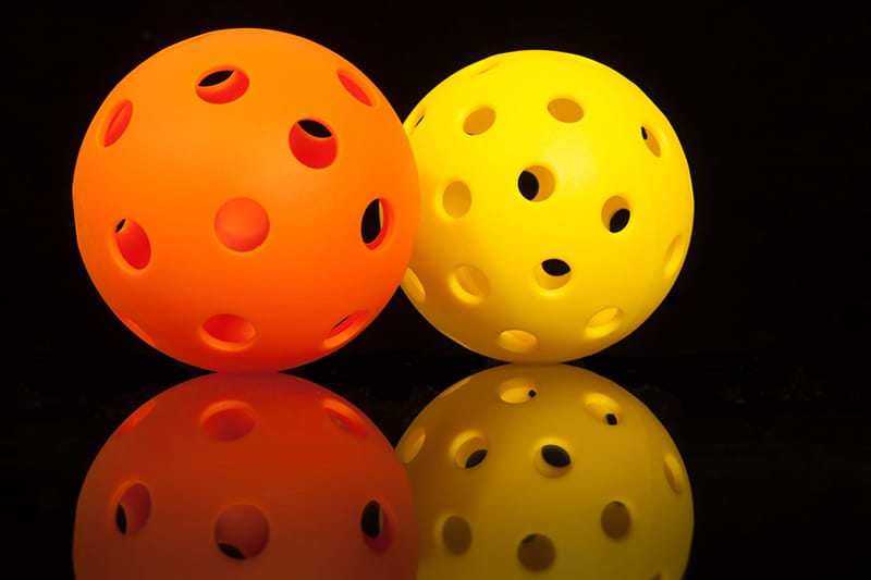 Mirrored Pickleballs...Orange & Yellow Pickleballs on a Black ba AdobeStock 194795473