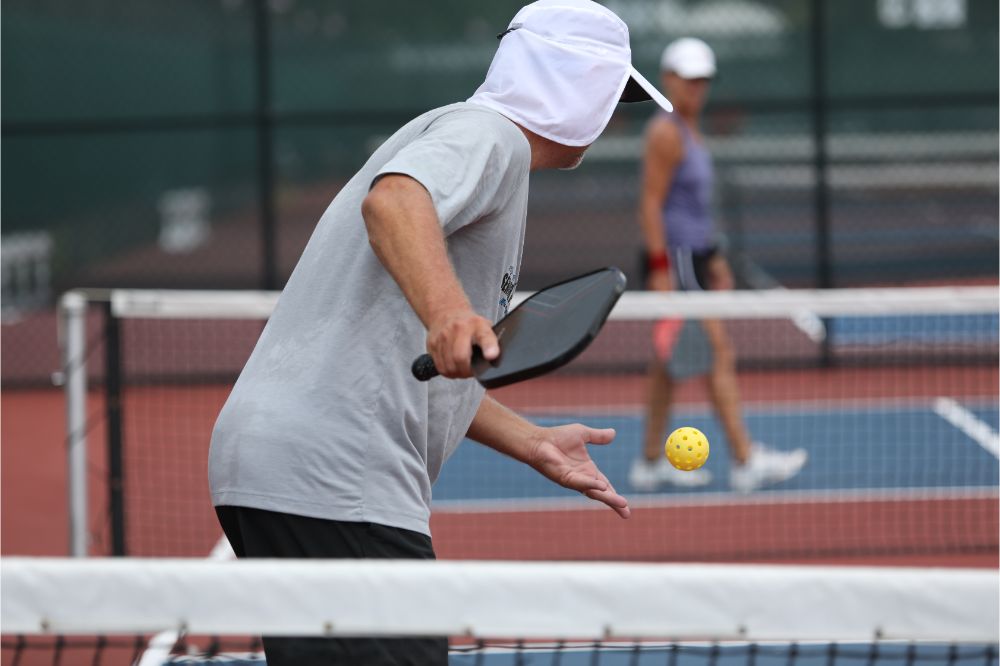 What Is a Let in Pickleball? 2 A senior athlete serves during a tournament pickleball match.